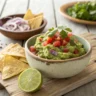 Bowl of chunky guacamole with tortilla chips and lime