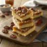 Stack of pecan shortbread bars topped with caramelized pecans