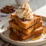 Stack of pumpkin french toast slices topped with syrup and whipped cream