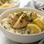 lemon herb chicken and rice served in a bowl with herbs and lemon