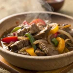 Bowl of Crock Pot Pepper Steak with bell peppers and onions