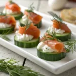 Smoked salmon cucumber bites topped with cream cheese and dill on a platter