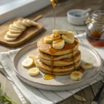 Stack of Banana Pancakes with syrup and banana slices