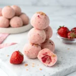 Strawberry cheesecake protein balls stacked on a plate