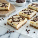 Cannoli cheesecake bars with creamy filling and chocolate drizzle.