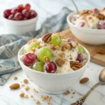 Creamy grape salad with red and green grapes topped with brown sugar and pecans.