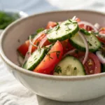 Cucumber tomato salad with herbs and light dressing in bowl