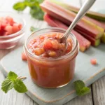 Rhubarb compote in glass jar with spoon and fresh rhubarb