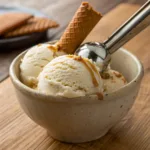 Creamy vanilla ice cream in bowl with vanilla bean specks and scoop