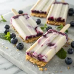 Blueberry cheesecake popsicles with graham cracker coating and blueberry swirl