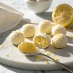 Lemon truffles dusted with sugar and lemon zest on a marble plate