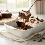 Homemade chocolate poke cake topped with chocolate whipped topping, chocolate shavings, and a moist chocolate crumb.