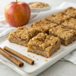 Apple oatmeal crumb bars with a cinnamon apple filling and golden buttery oat crumble layers.