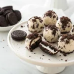 Homemade no-bake Oreo cheesecake bites coated with crushed Oreo cookies on a serving platter.