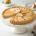 Classic pear tart with golden pastry, almond cream, thinly sliced pears, and a glossy caramelized finish.
