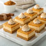 Homemade pumpkin cheesecake bars with a graham cracker crust and creamy pumpkin cheesecake filling on a serving platter.
