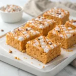 Homemade pumpkin spice Rice Krispie treats topped with white chocolate drizzle and pumpkin pie spice.